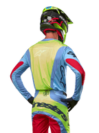 Motocross-Fahrer von hinten im Alpinestars 2024 Techstar Ocuri Trikot, Hellblau mit neongelber Rückseite und roten Ärmelakzenten, passende Motocross-Hose und neongelber Helm, abgestimmtes Outfit für Offroad-Rennen