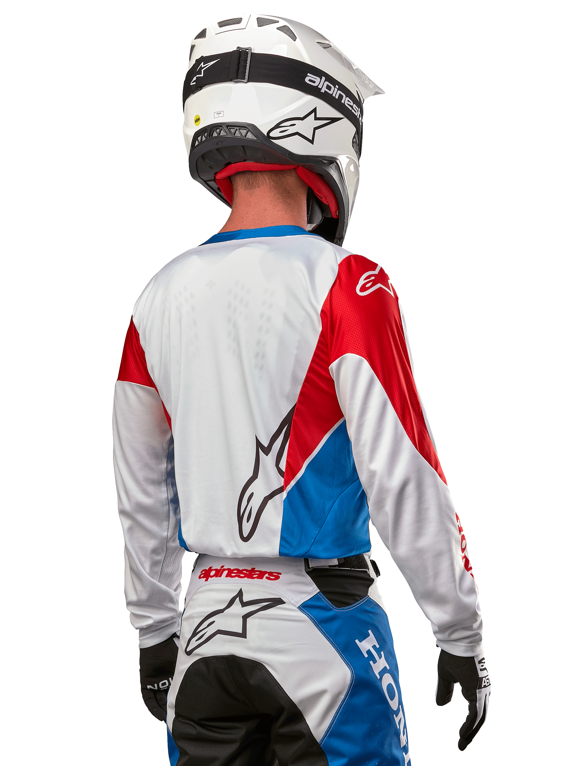 Motocross rider wearing the Alpinestars Honda Racer Iconic Jersey, back view, White with Bright Blue and Bright Red panels, featuring prominent Alpinestars logo on the back, paired with a white motocross helmet and matching racing pants.