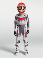 Alpinestars Supertech Jugend-Trikot Swan und Gear Set, Motocross-Outfit für junge Fahrer, Grau und Weiß mit roten Akzenten.