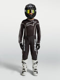 Alpinestars Fluid Apex V2 Jugend-Trikot und Gear Set, Motocross-Outfit in Schwarz und Silber mit weißen Stiefeln.
