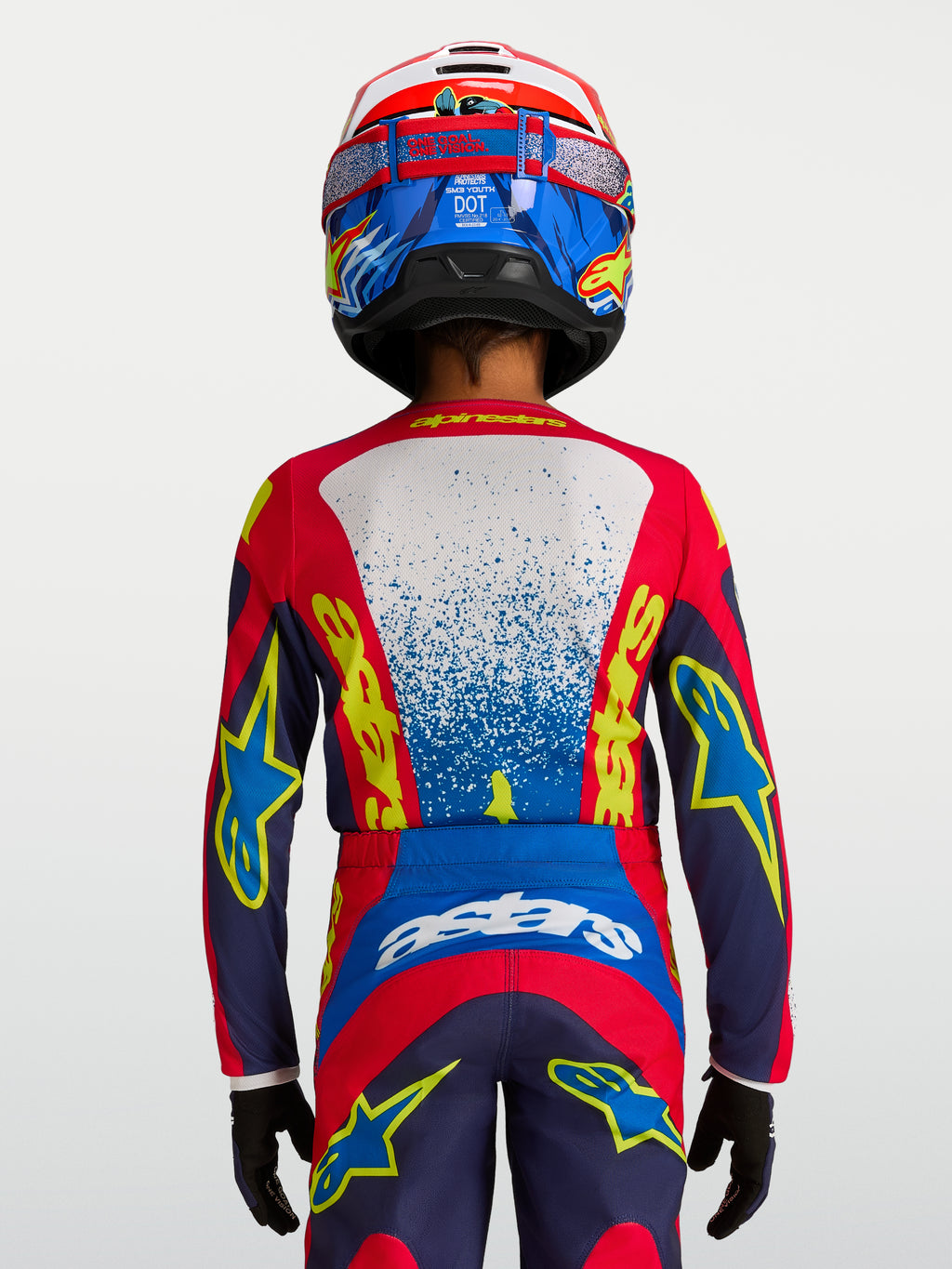 Alpinestars Fluid Jugend-Trikot Drag 2027, technisches Motocross-Trikot in Blau und Rot, Rückansicht auf einem jungen Fahrer, feuchtigkeitsableitendes Material, ergonomischer Schnitt für Offroad-Rennen.