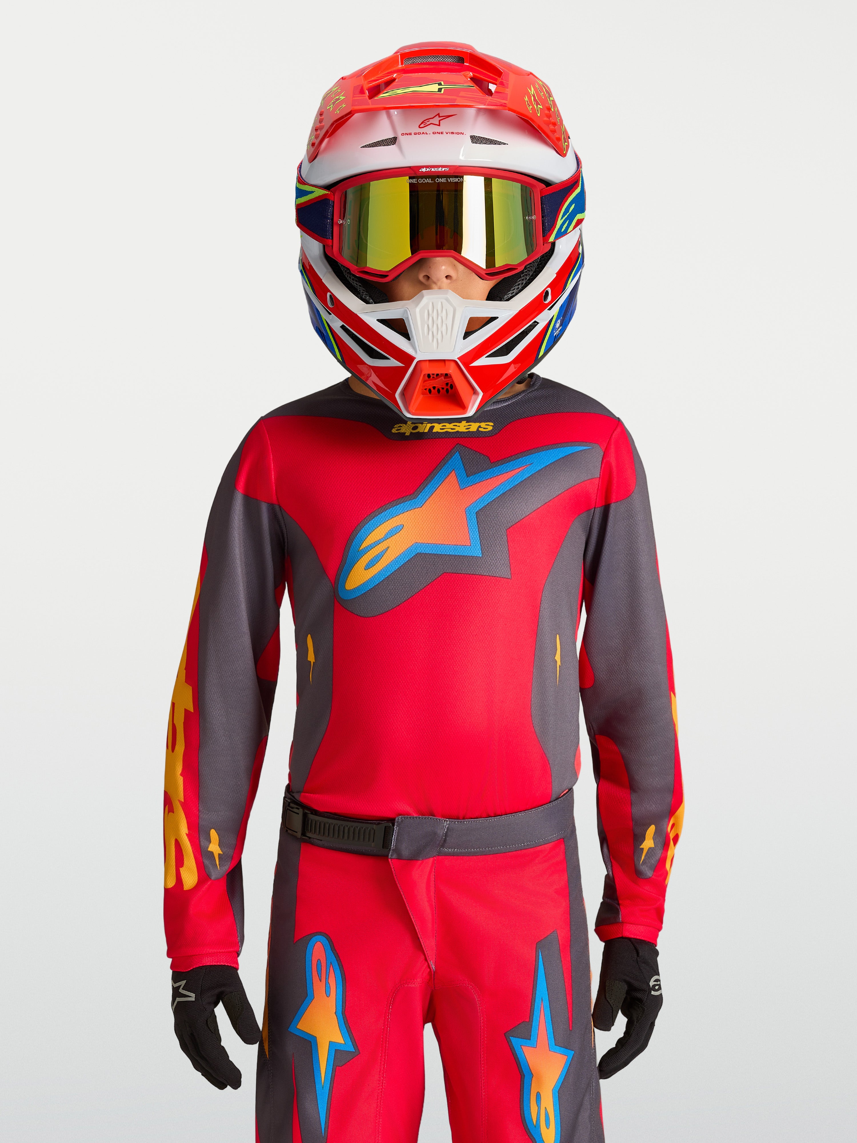 Alpinestars Fluid Hunt Jugend-Trikot 2027, Motocross-Bekleidung in Rot und Grau, getragen von einem Model mit Rennhelm.