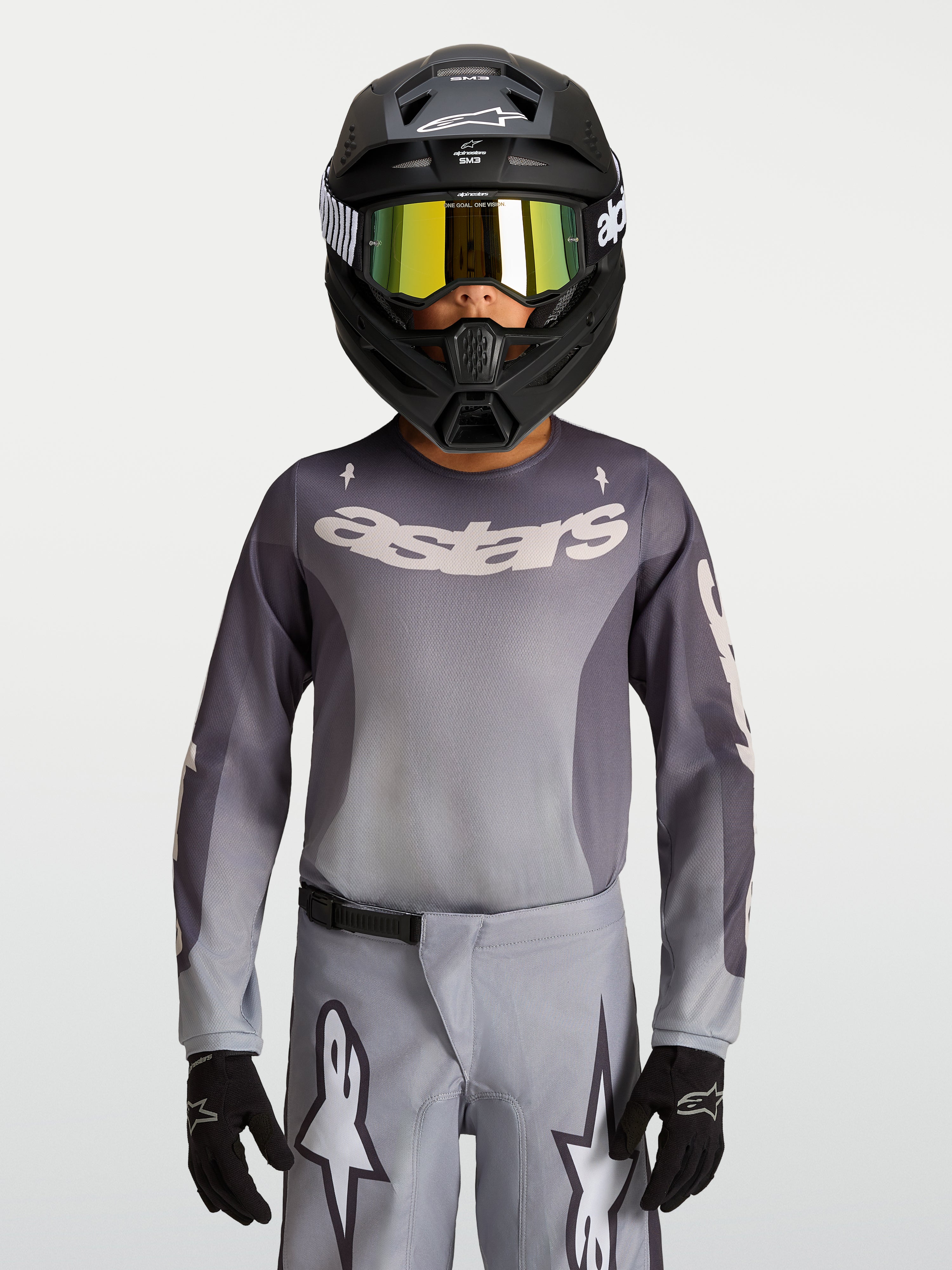 Alpinestars Fluid Jugend-Trikot Amber 2027, atmungsaktives Motocross-Trikot für Offroad, Grau und Sand, getragen mit Helm.