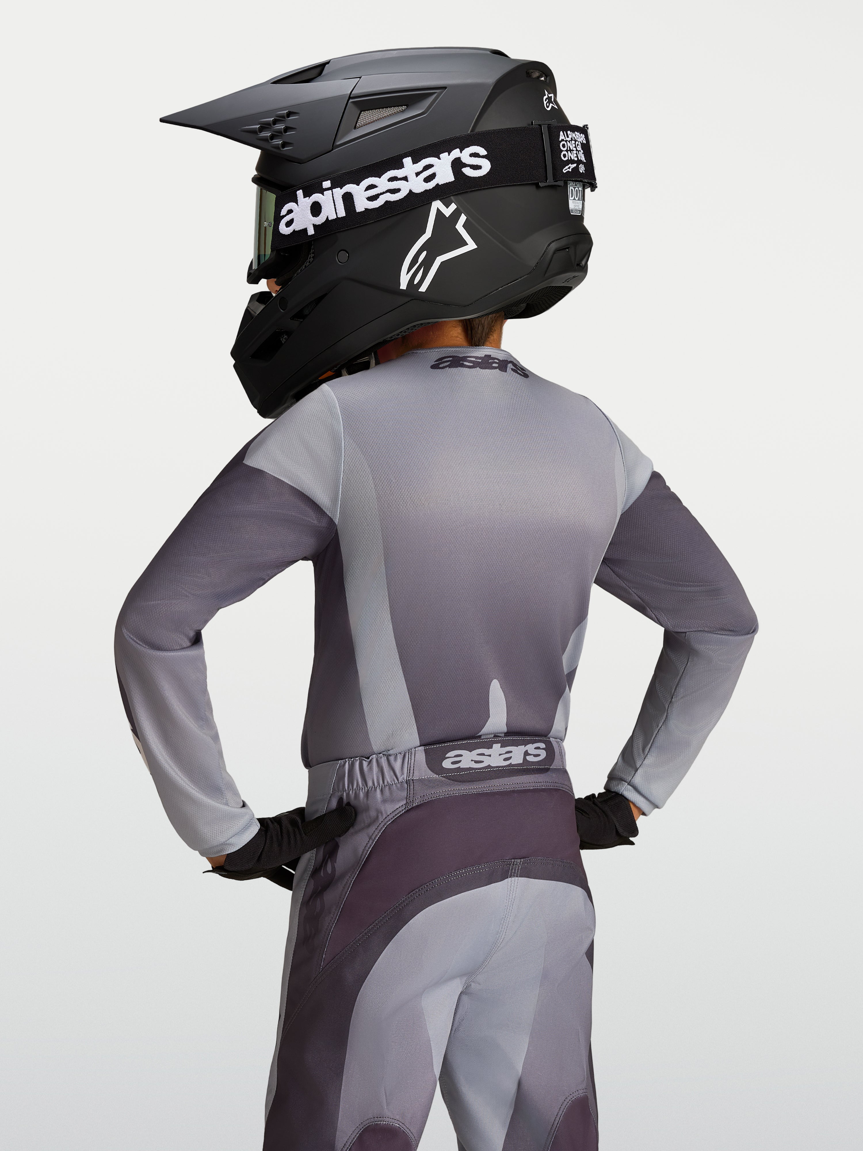 Alpinestars Fluid Jugend-Trikot Amber, Motocross-Trikot in Grau und Sand, Rückansicht eines jungen Fahrers mit Helm.