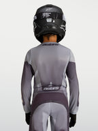 Alpinestars Fluid Jugend-Trikot Amber 2027, Motocross-Trikot für die Jugend, Sand und Grau, atmungsaktives Polygewebe, Rückansicht eines jungen Fahrers mit Helm.