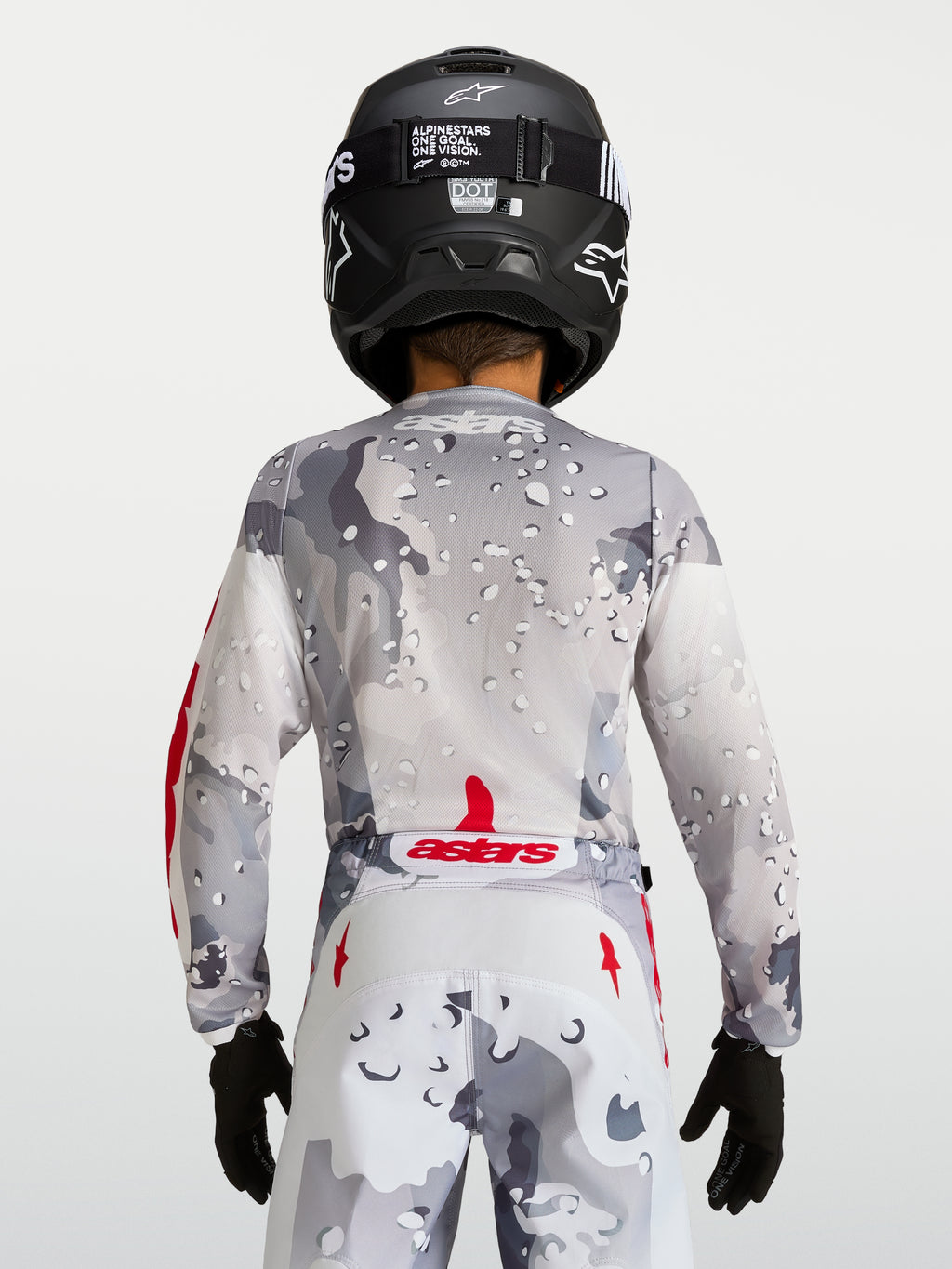 Alpinestars Fluid Jugend-Trikot Lone 2027, graues Camo-Motocross-Trikot, Rückansicht mit roten Akzenten und schwarzem Helm.
