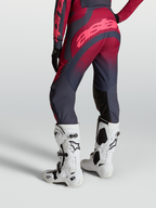 Alpinestars Stella Techstar Swan Hose von hinten, Crimson und Dunkelgrau, mit weißen Tech 10 Motocross-Stiefeln.
