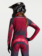 Alpinestars Stella Techstar Trikot Swan, Damen Motocross Trikot, Rot und Dunkelgrau, feuchtigkeitsableitendes Stretchmaterial, Rückansicht auf Model mit Helm.