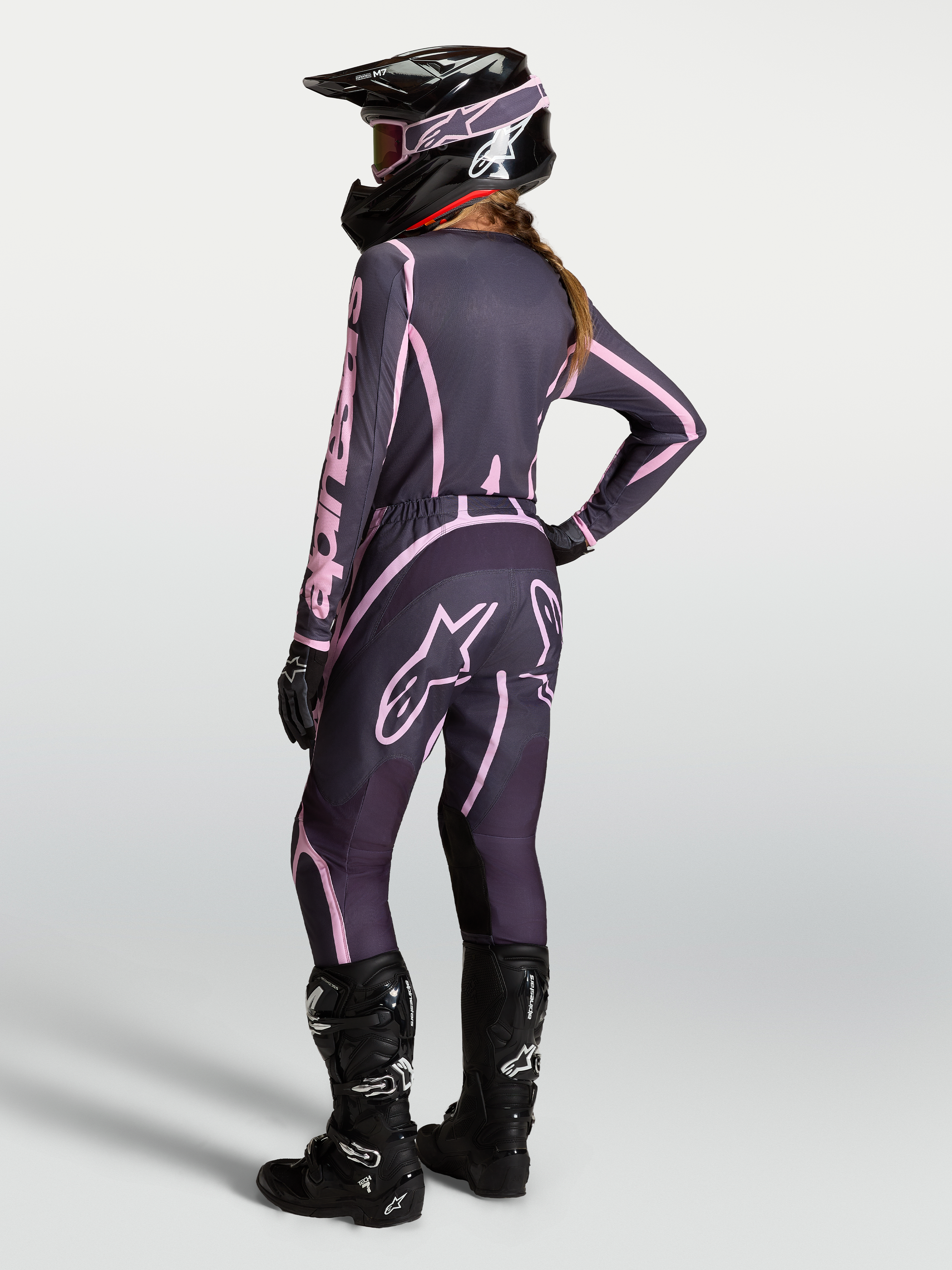 Alpinestars Stella Fluid Apex V2 Trikot und Gear Set, Damen-Motocross-Ausrüstung in Grau und Pink mit schwarzen Stiefeln.