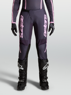 Alpinestars Stella Fluid Apex V2 Hose, Damen-Motocross-Hose in Grau und Pink, Modell an der Frontansicht mit Ratschenverschluss, 600D-Polygewebe, kombiniert mit schwarzen MX-Stiefeln und Handschuhen.