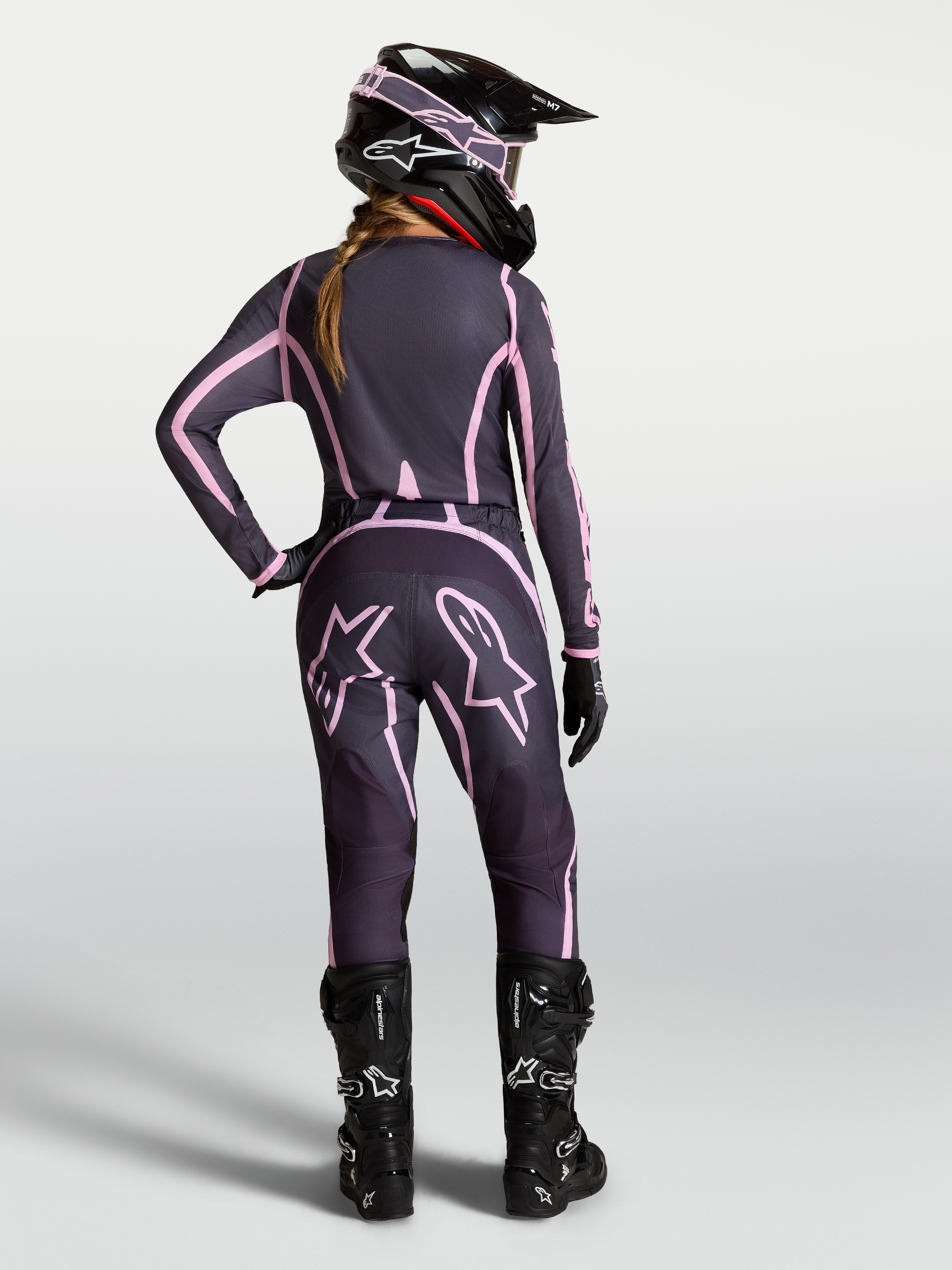 Alpinestars Stella Fluid Apex V2 Hose, Damen-Motocrosshose in Grau und Pink, Rückansicht einer Fahrerin mit kompletter MX-Ausrüstung, ergonomische Passform für Offroad-Einsätze