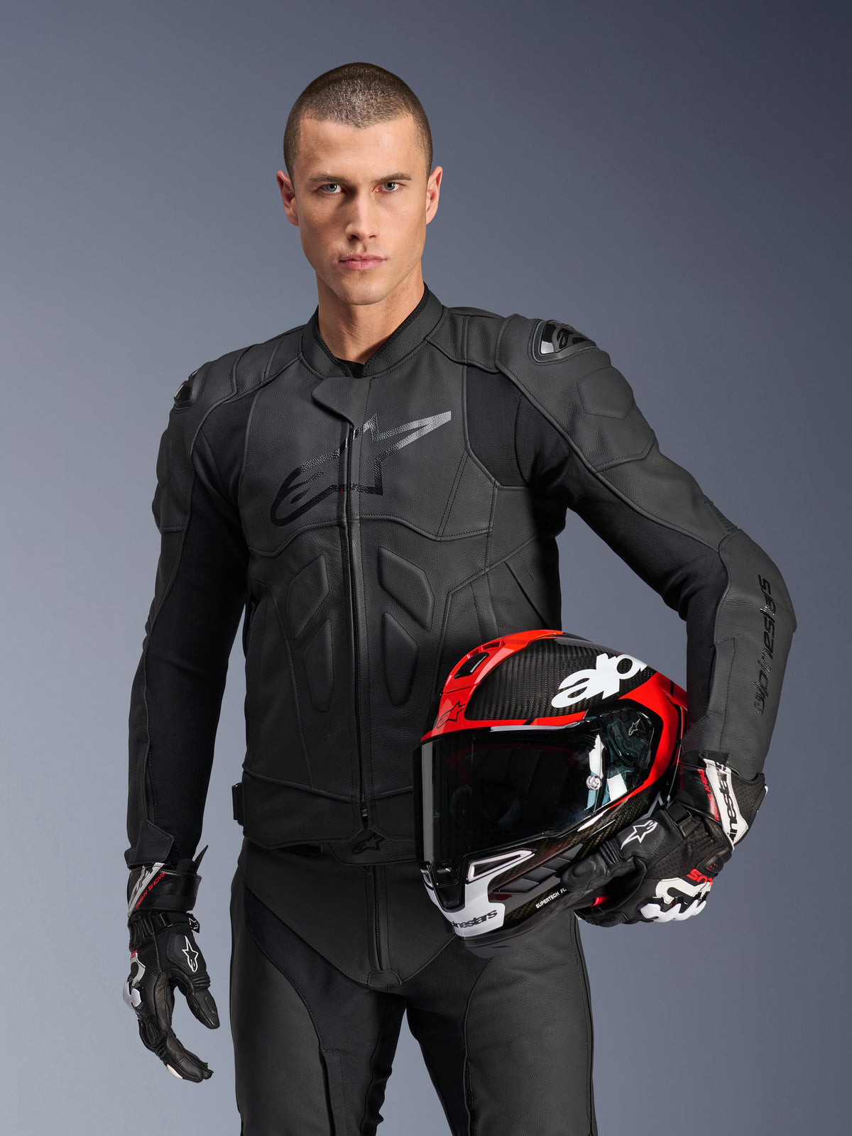 Alpinestars Dusk Leather Jacket, Black Men's Motorcycle Racing Jacket with Nucleon PLASMA armor and a red helmet.