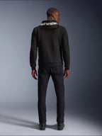 Alpinestars Chrome V2 Sport Hoodie, Motorcycle Hoodie, Black, back view of model wearing black tech fleece hoodie with white Alpinestars logo on the hood, paired with black pants and boots, casual urban riding style