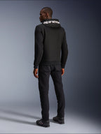 Alpinestars Chrome V2 Sport Hoodie, Black, rear view showing white Alpinestars branding on the hood, worn with black pants and riding shoes, casual urban motorcycle apparel with an athletic silhouette
