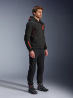 Alpinestars Chrome Air Sport Hoodie, Schwarz Rot Fluo, urbaner Motorrad-Hoodie aus Tech-Fleece, kombiniert mit schwarzer Hose und Motorradstiefeln, mit Mesh-Belüftungseinsätzen und fluoreszierend roten Logos auf Brust und Ärmel.