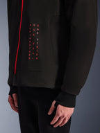 Alpinestars Radium Tech Hoodie, Urban Motorcycle Jacket, Black and Bright Red, close-up of front graphic with vertical red text "ALPINESTARS ONE GOAL ONE VISION", red zipper, and ribbed cuff with thumbhole.