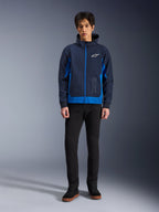 Alpinestars Radium Tech Hoodie, urbaner Motorrad-Hoodie in Night Navy und Royal Blue, winddichtes Technical-Shell, lässiges Streetwear-Design kombiniert mit schwarzer Hose und High-Top-Sneakern, mit weißem Logo-Branding auf der Brust.
