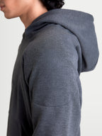 Alpinestars Ageless Kapuzenpullover, urbaner Herren-Motorradhoodie in Asphaltgrau meliert, Nahaufnahme des Seitenprofils mit gestrickter Materialkonstruktion und Schulterverstärkung am Model