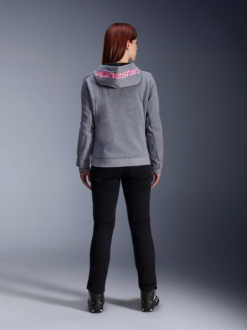 Alpinestars Stella Chrome V2 Sport Hoodie, Women's Motorcycle Hoodie, Gray Heather and Pink Fluo, back view showing pink Alpinestars logo on the hood, worn with black riding pants and boots, casual motorcycle apparel for women