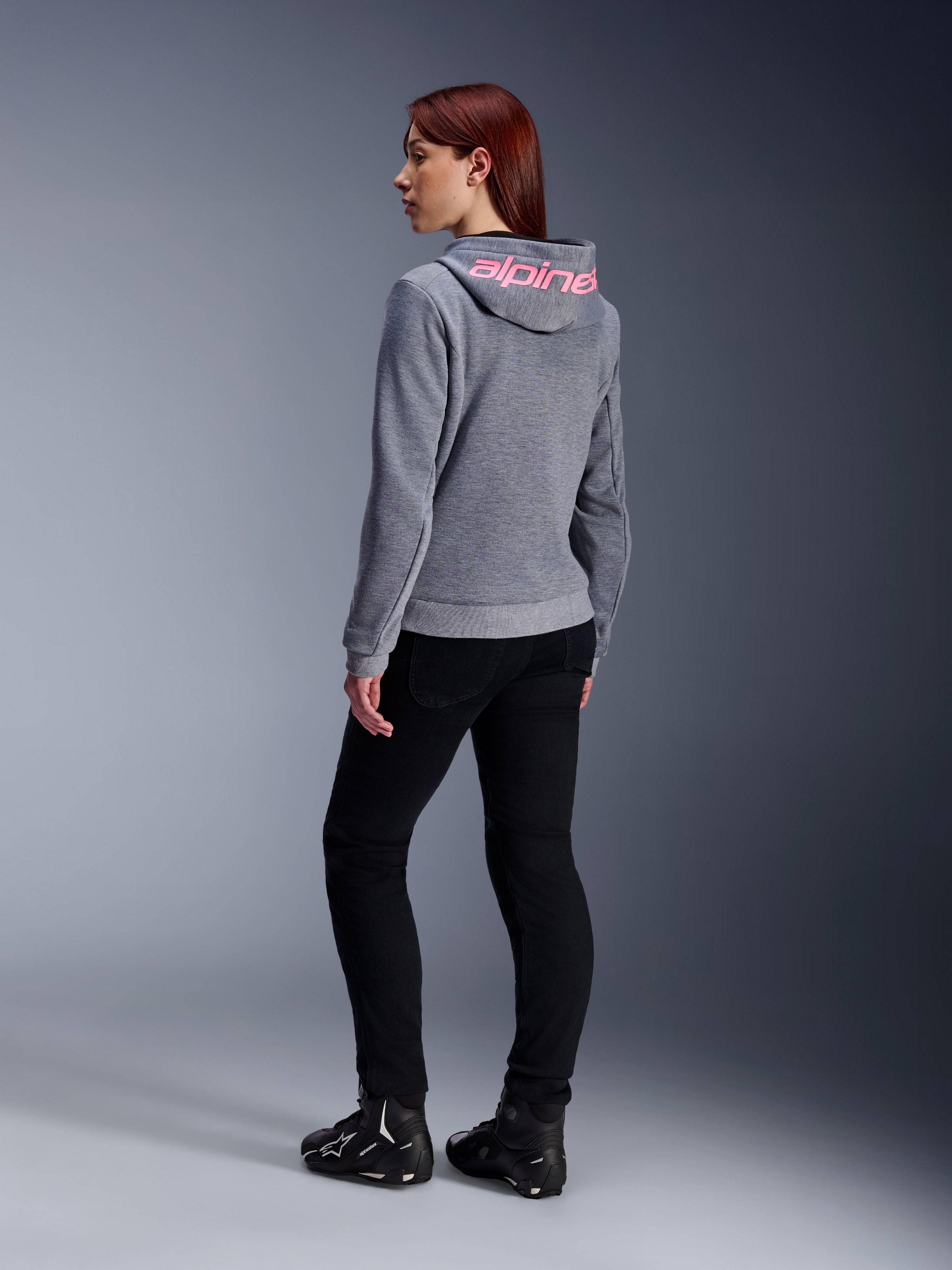 Alpinestars Stella Chrome V2 Sport Hoodie, Women's Motorcycle Hoodie, Gray Heather with Pink Fluo branding on hood, back view, worn with black pants and riding shoes, casual urban street style with motorcycle protection