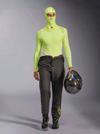 Alpinestars ZX Evo V3 Sturmhaube in Yellow Fluo, kombiniert mit passendem langärmeligem Base-Layer-Oberteil und dunkelgrauer Rennhose, männliches Model hält einen Carbon-Helm, professionelle Autorennsport-Ausrüstung