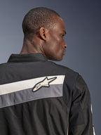 Alpinestars T-Dyno WR Jacke, Textil-Motorradjacke, Schwarz, Dunkelgrau und Ecru, Nahaufnahme des oberen Rückens und der Schulter mit horizontalen Streifen und Alpinestars-Sternlogo, von einem Model getragen, Heritage-inspiriertes Design für Straßenfahrten