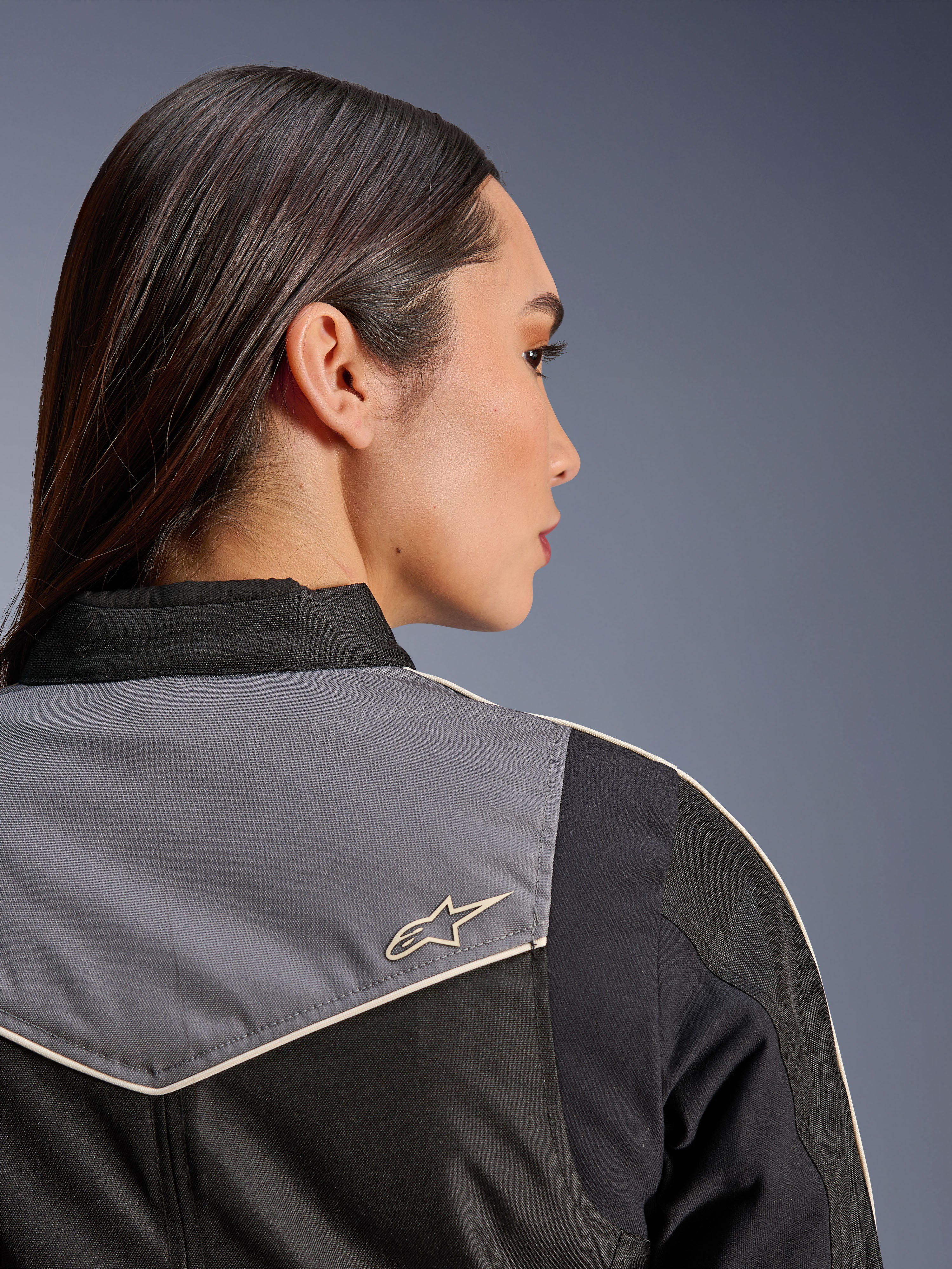 Alpinestars Stella T-Dyno WR Jacke, Damen-Motorradjacke, Schwarz, Dunkelgrau und Ecru, Nahaufnahme der Rückansicht von Schulter und Passe mit grauem Einsatz und ecrufarbenem Stern-Logo, Vintage-inspirierte Motorradausrüstung