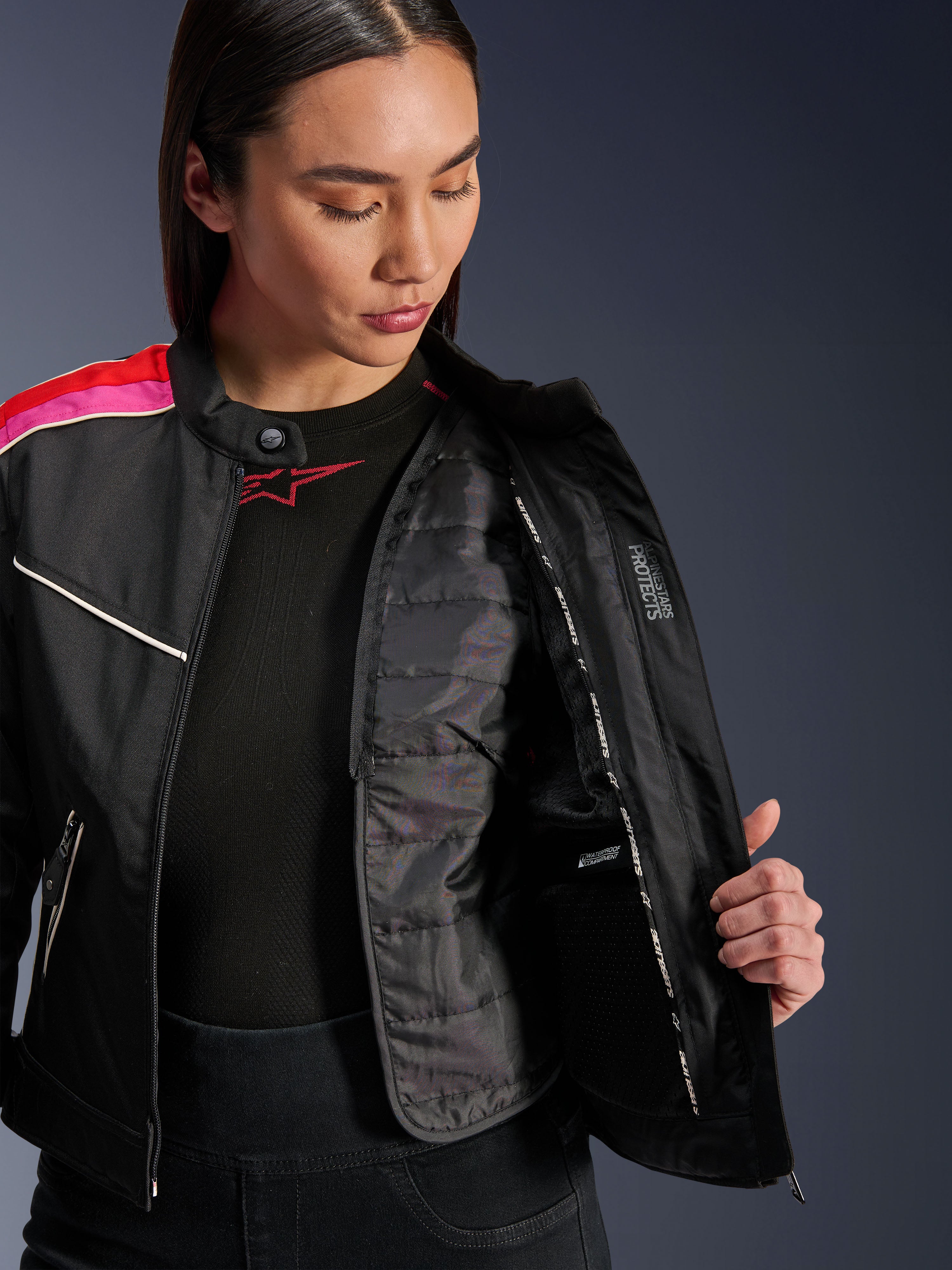 Alpinestars Stella T-Dyno WR Jacke, Textil-Motorradjacke in Schwarz, Bright Red und Fuchsia, geöffnet, um die innenliegende gesteppte Thermoweste und die wasserdichte Tasche zu zeigen, Vintage-inspirierte Biker-Passform für Damen