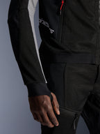 Alpinestars Troop-Air Pro Jacke, hochwertige gepanzerte Air-Jacke, Schwarz, Ash Gray und Bright Red, mit 2D-Tech-Mesh-Konstruktion für Belüftung, esche-grauen Ärmeleinsätzen, rotem Reißverschluss-Akzent und integrierten Daumenloch-Manschetten, getragen mit passender Hose.