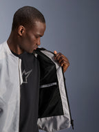 Männliches Model trägt die Alpinestars C-1 Air Jacke in Silber und öffnet die Vorderseite, um das schwarze Tech-Mesh-Innenfutter und eine wasserdichte Innentasche mit Reißverschluss zu zeigen.