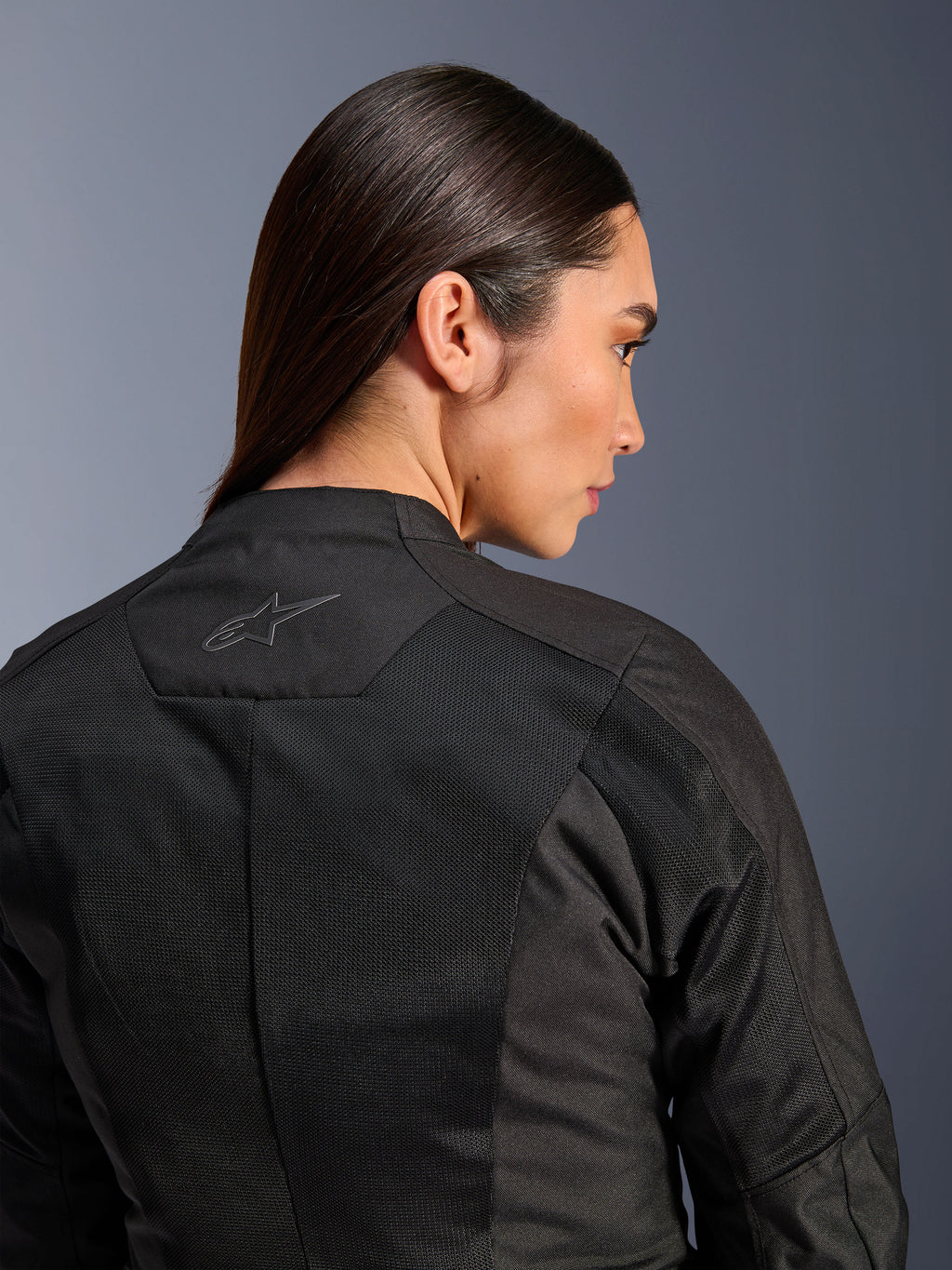 Alpinestars Stella C-1 Air Damenjacke, Textil-Motorradjacke, Schwarz, Nahaufnahme der Rückansicht mit Tech-Mesh-Belüftungseinsätzen und einem reflektierenden Stern-Logo am oberen Rücken, moderne urbane Fahrausrüstung