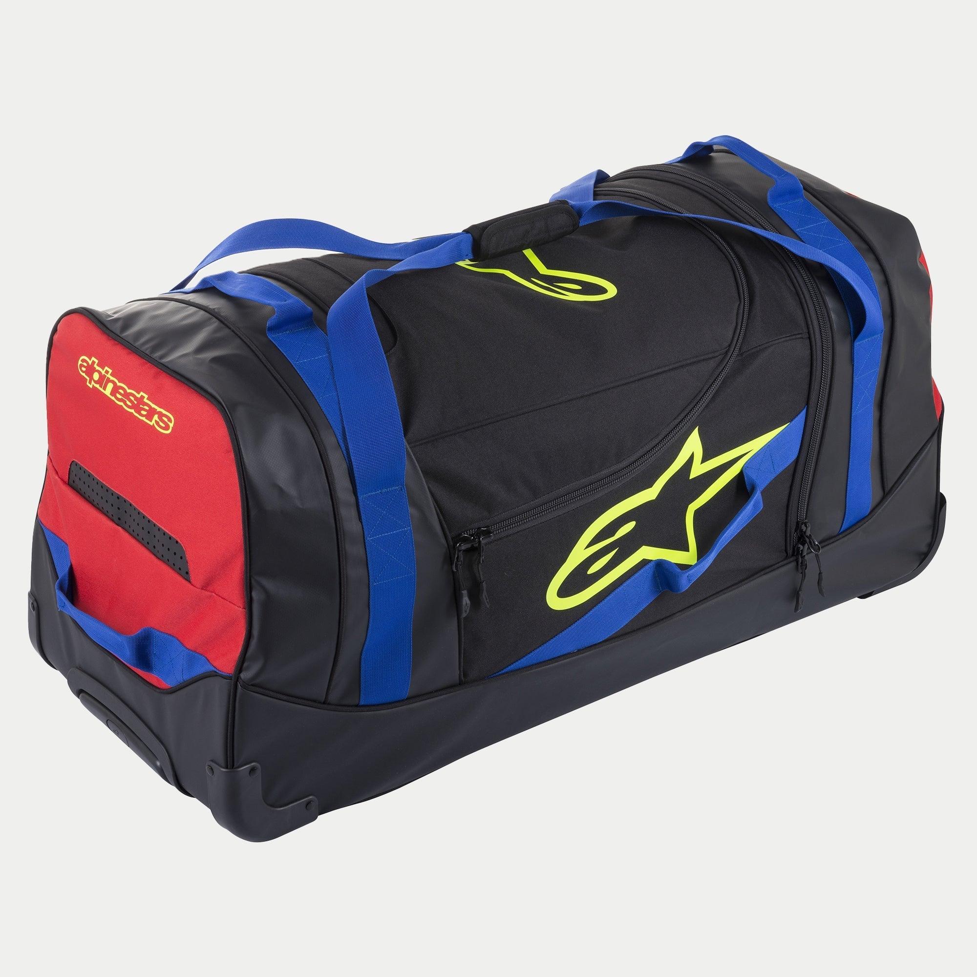 Alpinestars Komodo Reisetasche, Rollentasche für Ausrüstung, Schwarz, Blau, Rot und Fluo-Gelb, mit blauen Gurtbandgriffen, einem roten Seitenpaneel und fluoreszierend gelben Logos, robuste Konstruktion mit Rollen für den Transport von Motocross- und Rennausrüstung