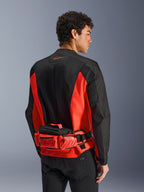 Alpinestars MM93 Waist Bag, Motorcycle Waist Pack, Bright Red and Black, worn over a matching black and red riding jacket, featuring zippered compartments and Marc Marquez MM93 branding, durable textile construction for motorcycling