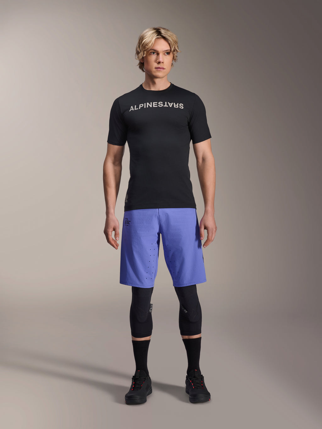 Alpinestars A-Aria Lite Short in Baja Blue, MTB-Shorts für Herren, getragen mit einem schwarzen Kurzarm-Trikot und schützenden Knieschonern, mit Laser-Perforationen zur Belüftung, Mountainbike-Performance-Ausrüstung