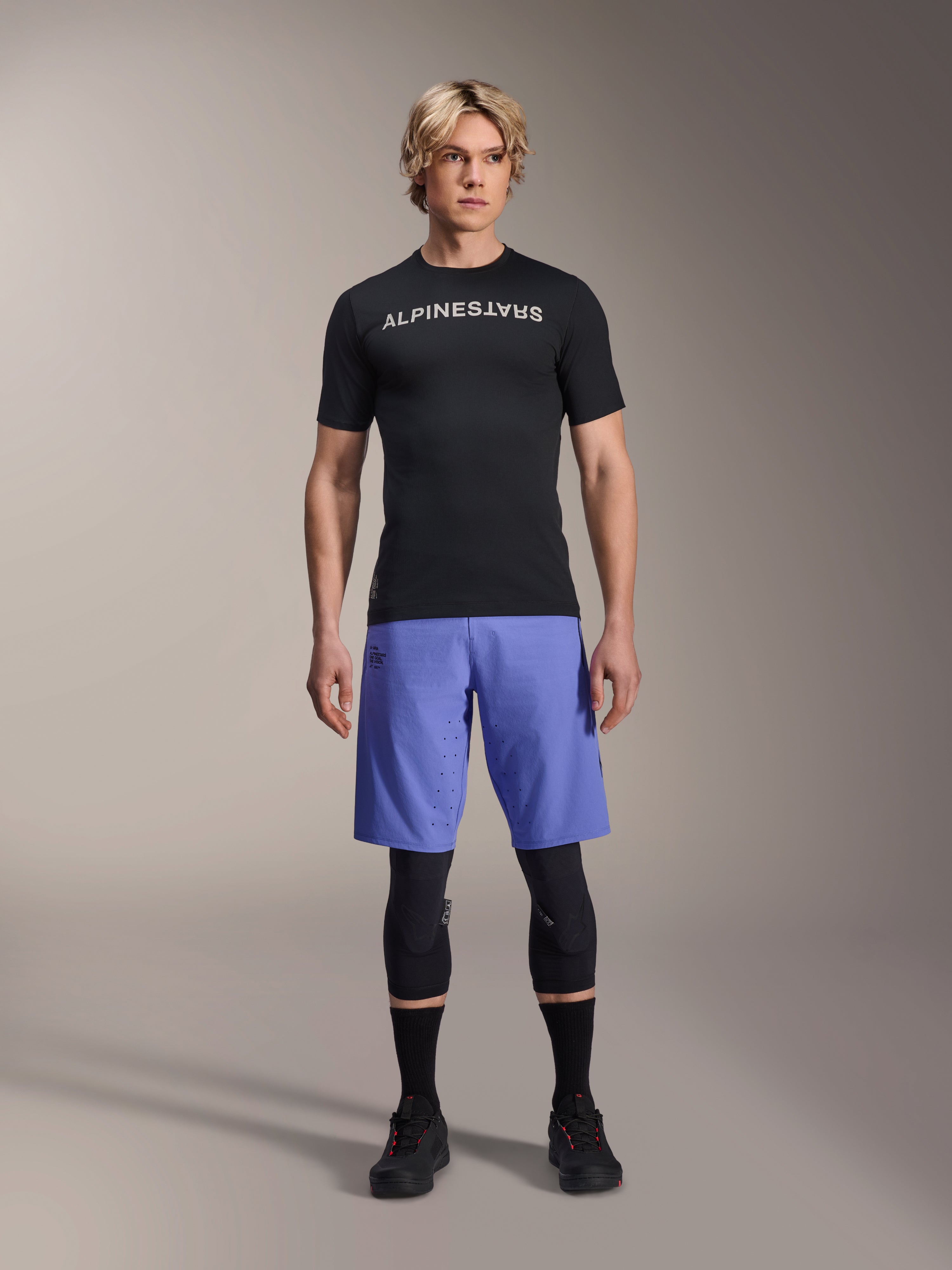 Alpinestars A-Aria Lite Short in Baja Blue, MTB-Shorts für Herren, getragen mit einem schwarzen Kurzarm-Trikot und schützenden Knieschonern, mit Laser-Perforationen zur Belüftung, Mountainbike-Performance-Ausrüstung