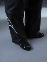 Alpinestars RSRV Starline Schuhe, Schwarze Hose mit weißem Logo an der Seite, glatte Textur mit Nähten, schwarze Socken mit weißen und roten Designs, Lifestyle-Streetwear