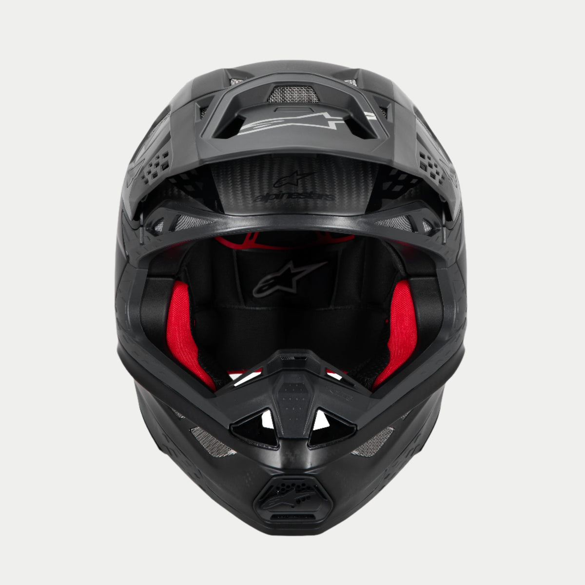 Alpinestars Supertech M10 Fame ECE 22.06 Helmet, Motocross Helmet, Black Carbon Matte and Glossy, front view with visible red interior padding, aerodynamic carbon fiber shell, ventilated design for off-road racing