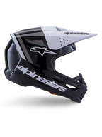 Alpinestars S-M3 Radium Helm, Motocross-Offroad-Helm, Schwarz, Weiß und Grau glänzend, mit einem kantigen aerodynamischen Design und Belüftungsöffnungen, Seitenansicht, glänzende Oberfläche mit grauen Streifen und ein weißes Visier mit Alpinestars-Branding