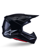Alpinestars S-M7 Solid Helmet, Motocross Racing Helmet, Glossy Black with White Star Logo and Red Accents, side profile featuring aerodynamic design with angular mesh vents and Supertech M7 branding on the visor.