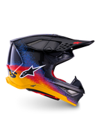 Alpinestars Limited Edition Supertech M10 Black Hole Helm, Motocross-Rennhelm, schwarze Schale mit rot-blau-gelbem Splatter-Farbverlauf, weißes Stern-Logo auf der Seite, aerodynamisches Profil mit netzabgedeckten Belüftungsöffnungen, rote Innenpolsterung und langes schwarzes Visier.