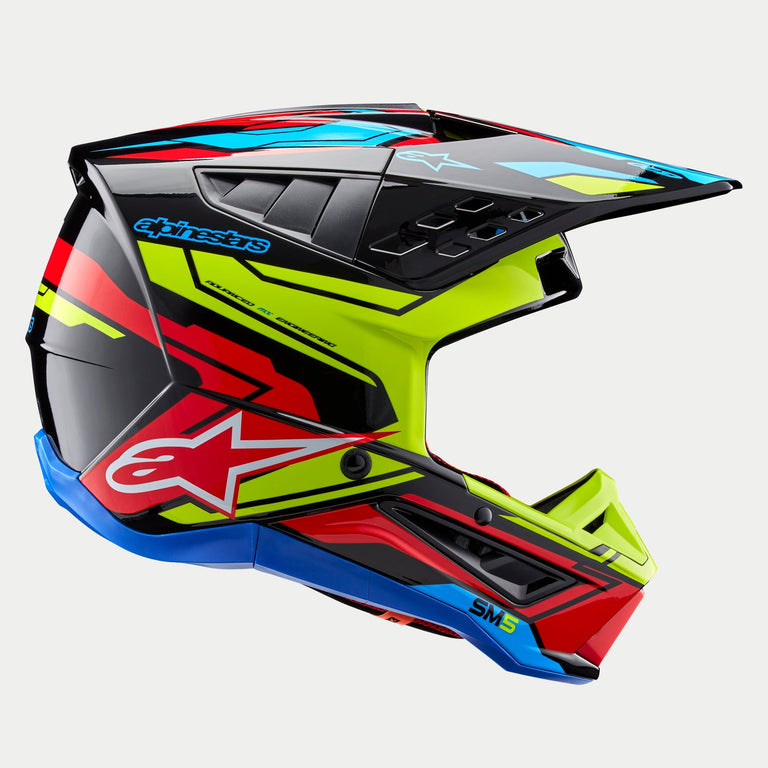Alpinestars S-M5 Action 2 Helm ECE, Motocross-Helm, Glänzendes Schwarz mit Grafiken in Gelb Fluo, Hellrot und Cyanblau, Seitenansicht mit aerodynamischer Schale, belüftetem Helmschirm und markantem Alpinestars-Branding auf der Seite, professioneller Schutz für den Offroad-Rennsport