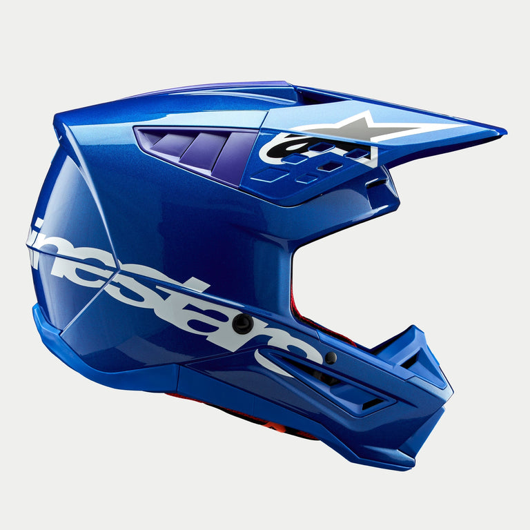 Alpinestars S-M5 Corp Helm ECE, Motocross-Helm in glänzendem Blau, Seitenprofil, markantes weißes Alpinestars-Branding auf der Seite, lila Akzente in den Belüftungsöffnungen, leichte aerodynamische Schale für Offroad-Performance