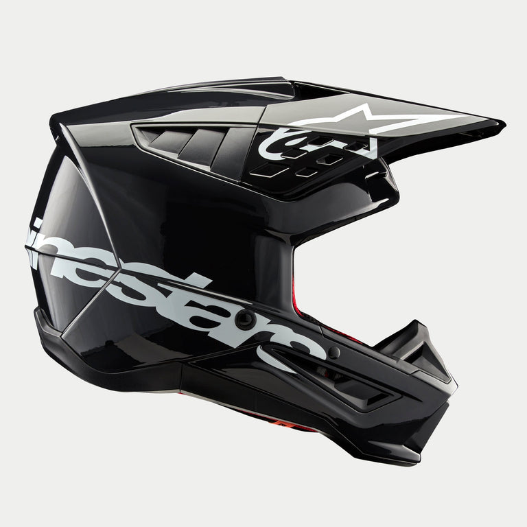 Alpinestars S-M5 Corp Helm, Motocross-Helm, Dunkelgrau glänzend, Seitenprofil-Ansicht mit großem weißen Alpinestars-Logo, weißes Stern-Logo auf dem Visier, schlanke aerodynamische Belüftungsöffnungen, glänzendes Finish, Offroad-Rennschutz