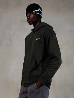Alpinestars Essentials Ageless Hoodie, Off Black, Male model wearing casual streetwear, dark charcoal stone-washed fleece with a small white star logo, paired with a black Alpinestars beanie and grey pants