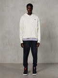 Alpinestars Essentials Ageless Zip Hoodie, casual streetwear, off-white with subtle black chest logo, full-zip front, hooded design, relaxed fit, styled with black sweatpants and sneakers