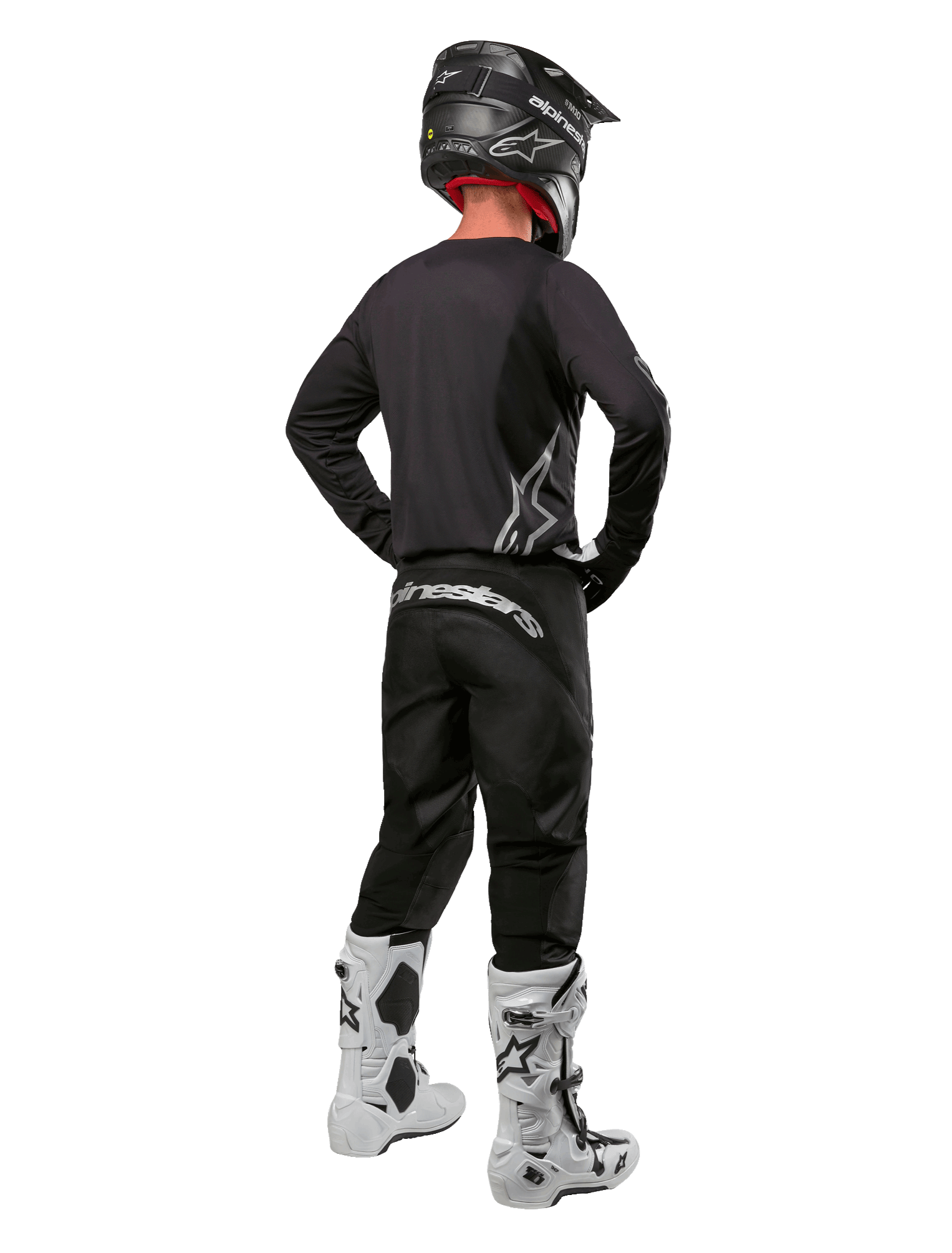 Alpinestars 2024 Fluid Graphite Gear Set, Motocross-Fahrer in der Rückansicht, graphitgraues Jersey und Hose mit silbernem Alpinestars-Branding, schwarzer Helm und weiße Motocross-Stiefel, athletische Passform für den Offroad-Einsatz