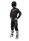 Alpinestars 2024 Fluid Graphite Ausrüstungsset, komplettes Motocross-Rennoutfit, Schwarz mit grauen und weißen Logos, bestehend aus Trikot und Hose mit passendem schwarzem Helm, weiß-schwarzen Handschuhen und Stiefeln, entwickelt für Offroad-Schutz