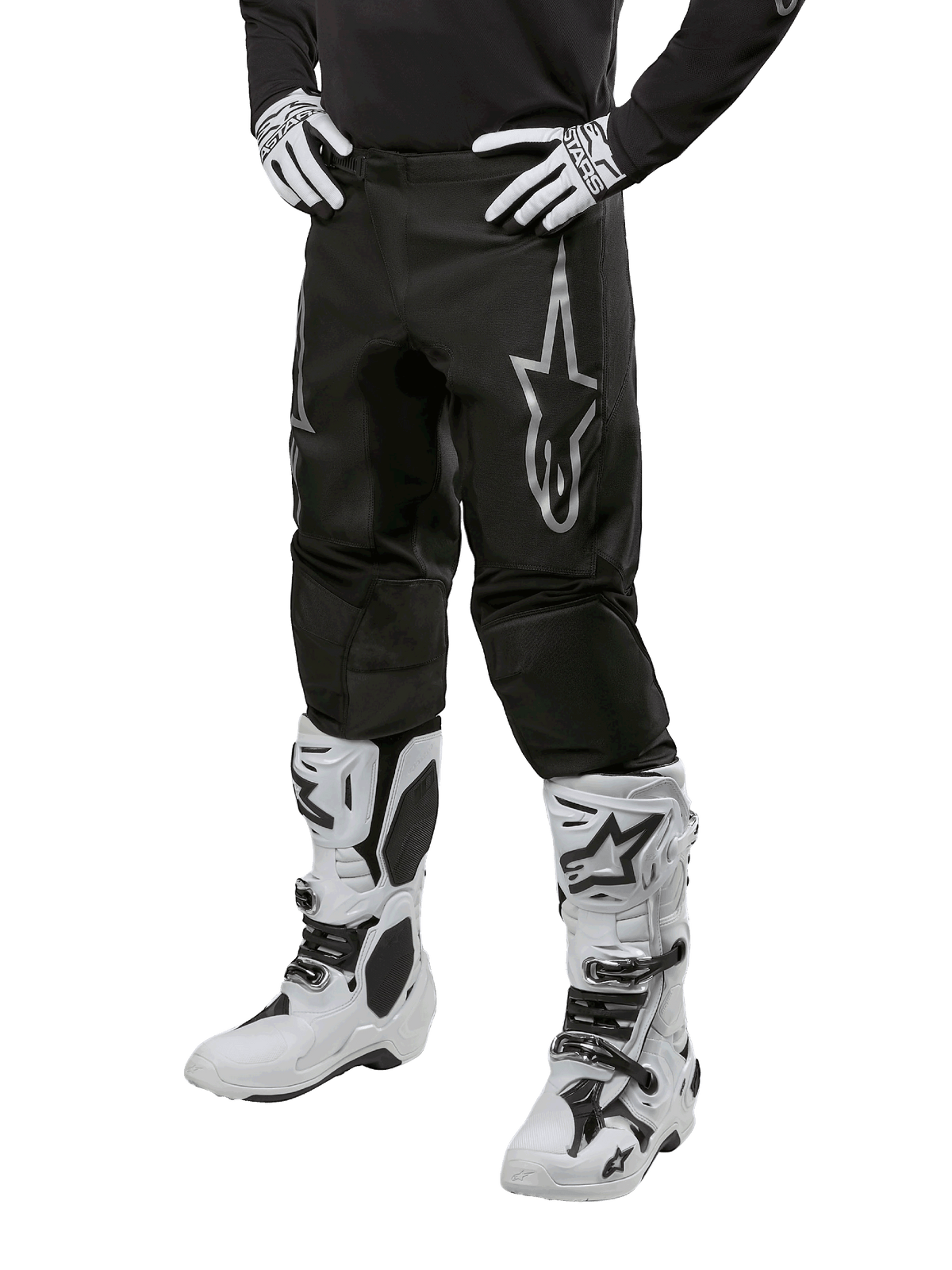 Alpinestars 2024 Fluid Graphite Hose, Motocross-Hose, Schwarz und Silber, mit silbernem Alpinestars-Logo auf dem Oberschenkel, gezeigt mit weißen Motocross-Stiefeln und Handschuhen, entworfen für Offroad-Motorradrennen