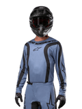 Motocross-Fahrer im Alpinestars 2024 Fluid Lurv Trikot, Hellblau und Schwarz, kombiniert mit einem schwarzen Helm und einer Brille, mit markanten schwarzen Grafikakzenten und Alpinestars Stern-Logo, sportliche Performance-Ausrüstung für Offroad-Rennen