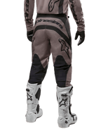Alpinestars 2024 Fluid Lurv Hose, Motocross-Hose, Mud Black, Rückansicht mit großem schwarzem Alpinestars-Logo auf dem Gesäß und schwarzen Wadenpaneelen, getragen mit weiß-schwarzen Motocross-Stiefeln und passendem Jersey.